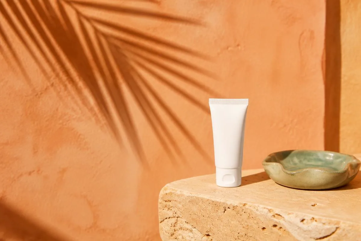 Small unlabeled white tube resting on folded cream linen in soft curtain light