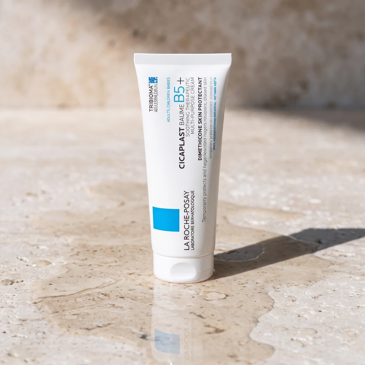 La Roche-Posay Cicaplast Baume B5+ tube on wet stone, with a hard shadow and a water reflection