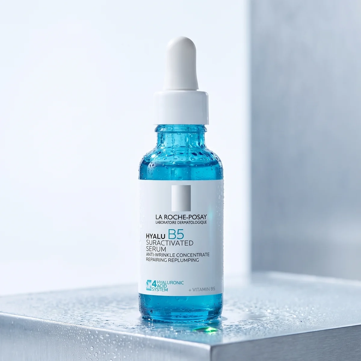 La Roche-Posay Hyalu B5 serum bottle on wet metal, with a white dropper and water droplets