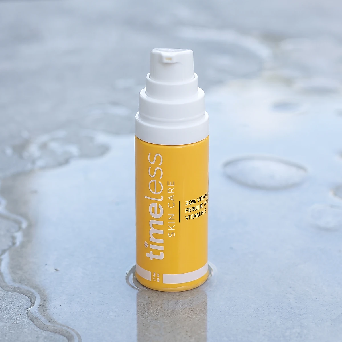 Timeless 20% Vitamin C serum pump bottle on wet gray stone, with a white cap and a soft reflection